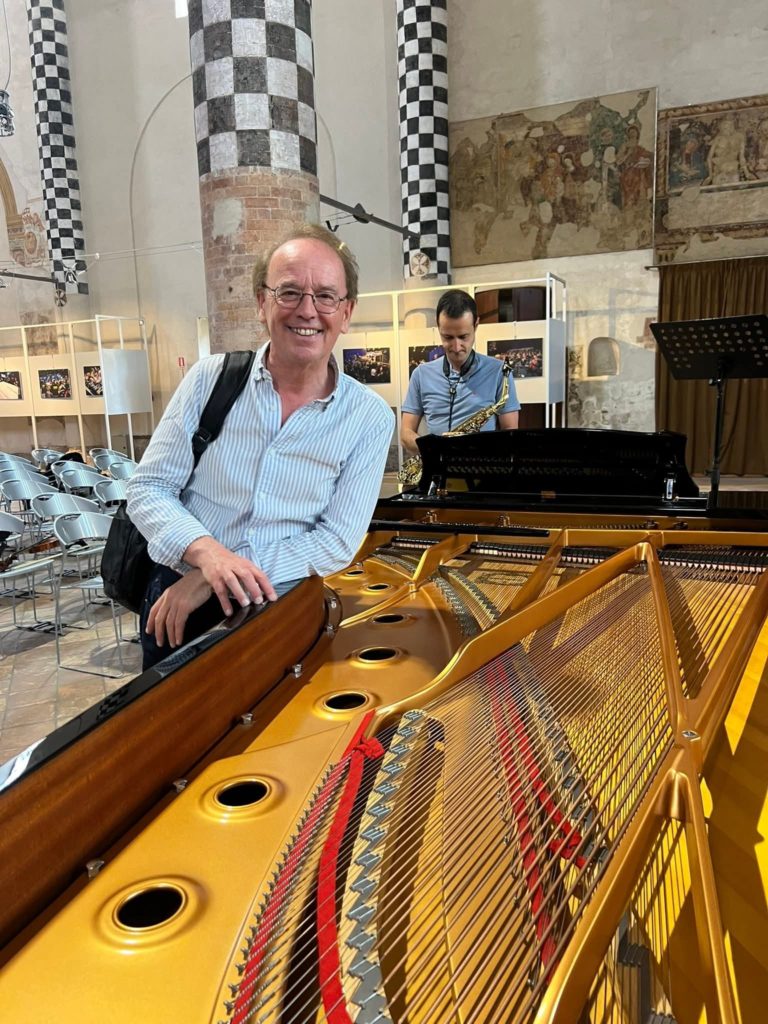 Patrick Dheur auprès du mécanisme d’un piano à queue dans une salle de concert